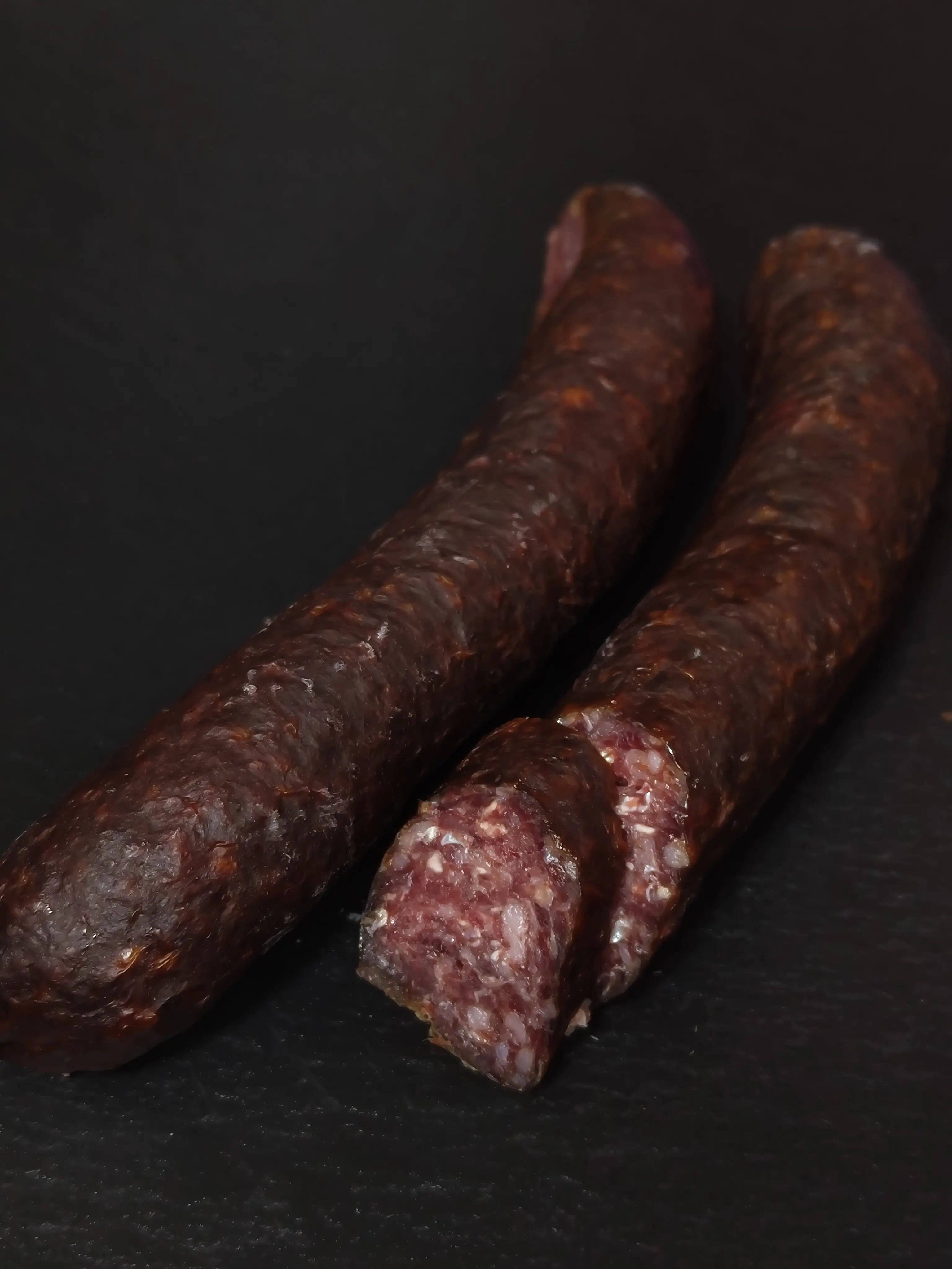 Selbstgefertigte Hirschkaminwurzn zum Jausnen oder Mitnehmen auf einer schwarzen Schieferplatte in Szene gesetzt