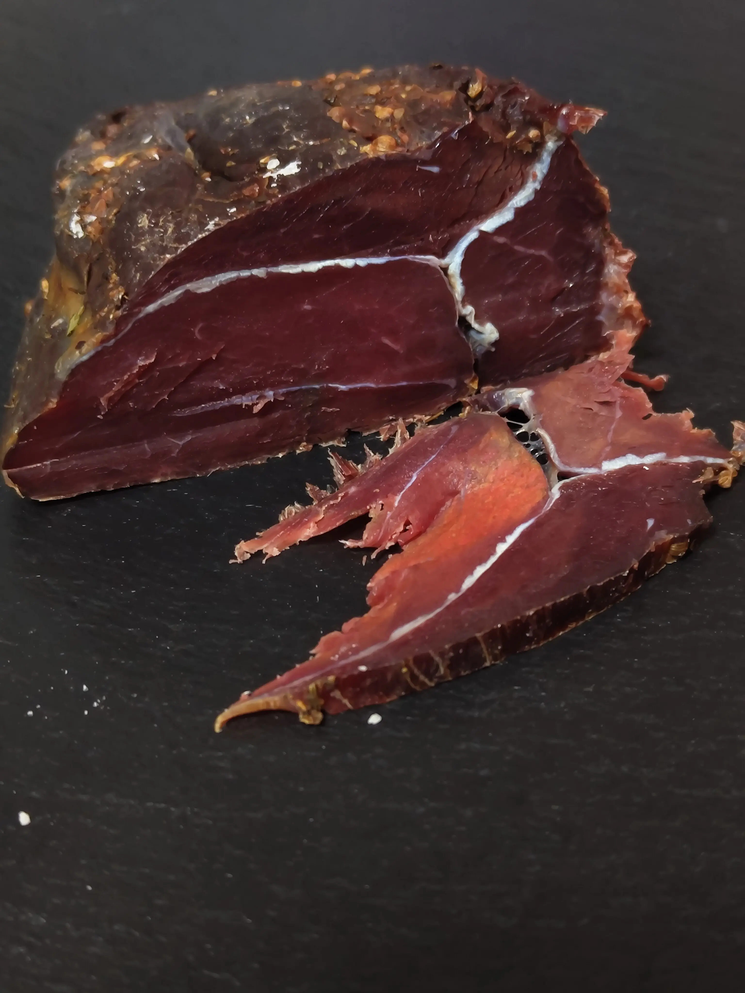 Geschmackvoller Hirschrohschinken zum Geniessen auf einer schwarzen Schieferplatte in Szene gesetzt